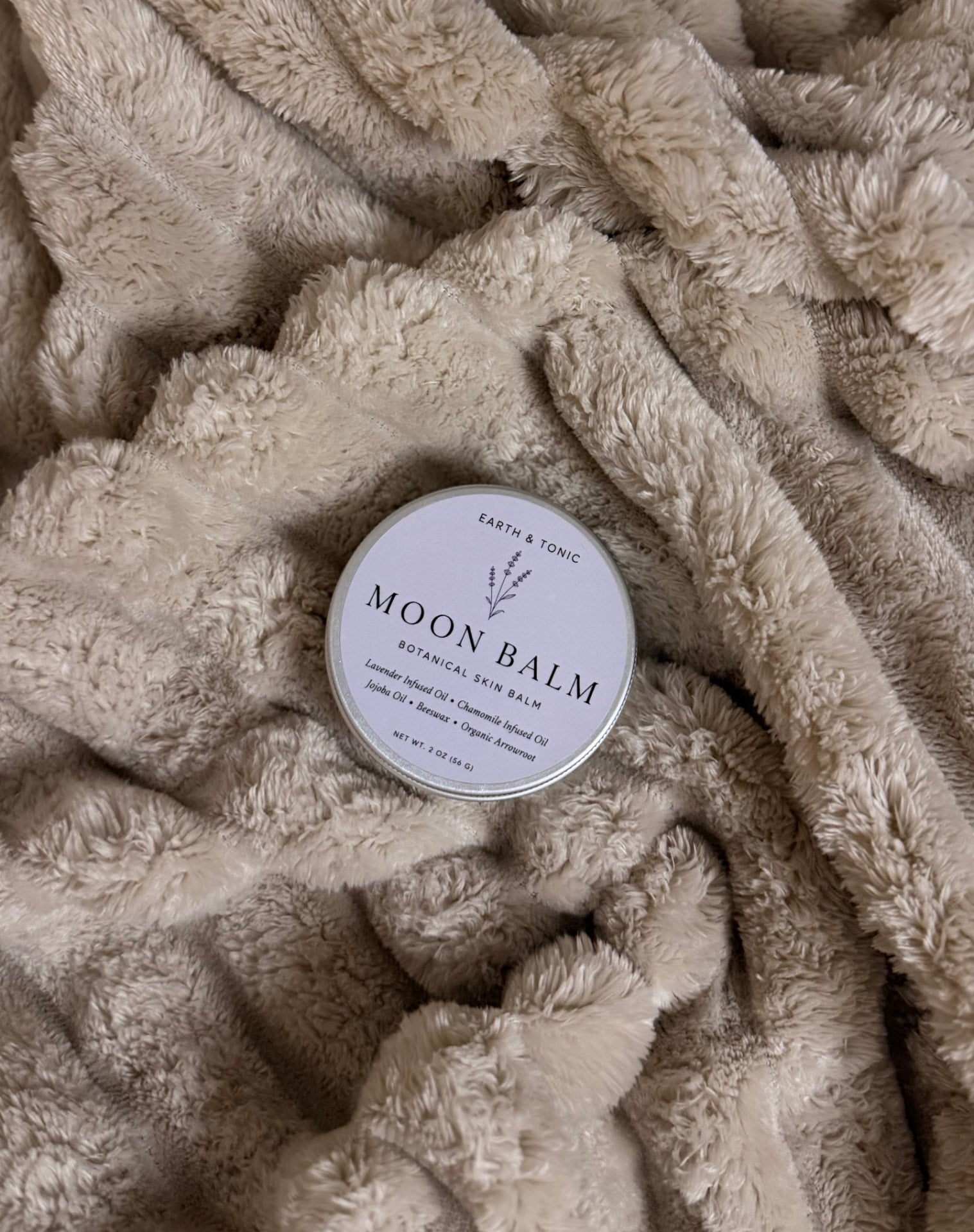 Moon Balm tin resting on a soft blanket